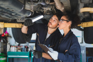 Two mechanics man and woman checking and repair maintenance a car in auto service garage